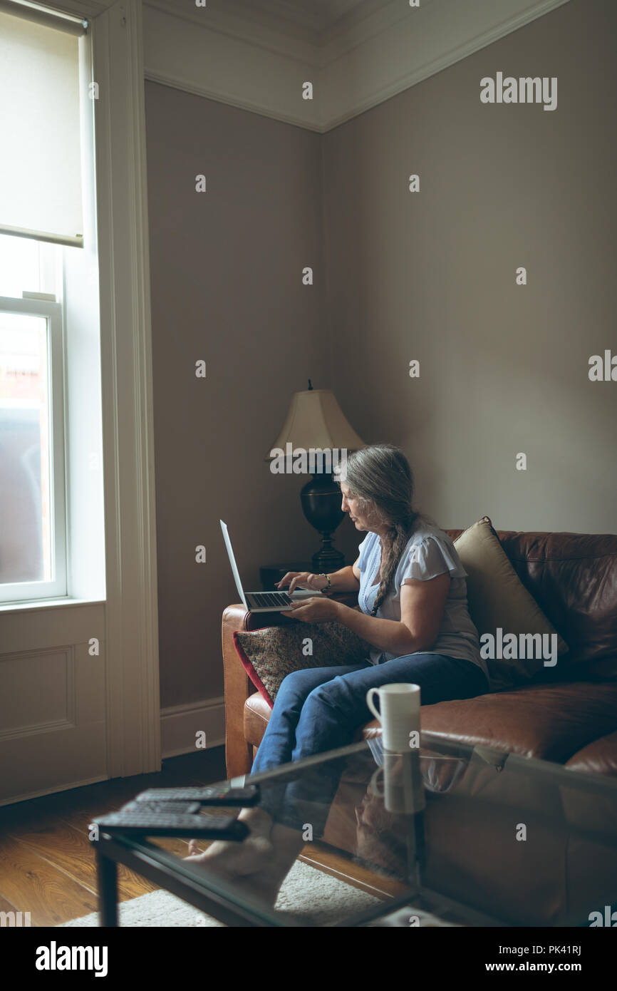 Senior woman using laptop in living room Stock Photo