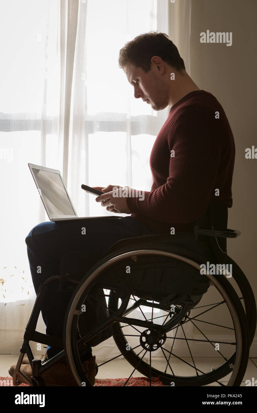 Disabled man using mobile phone at home Stock Photo Alamy