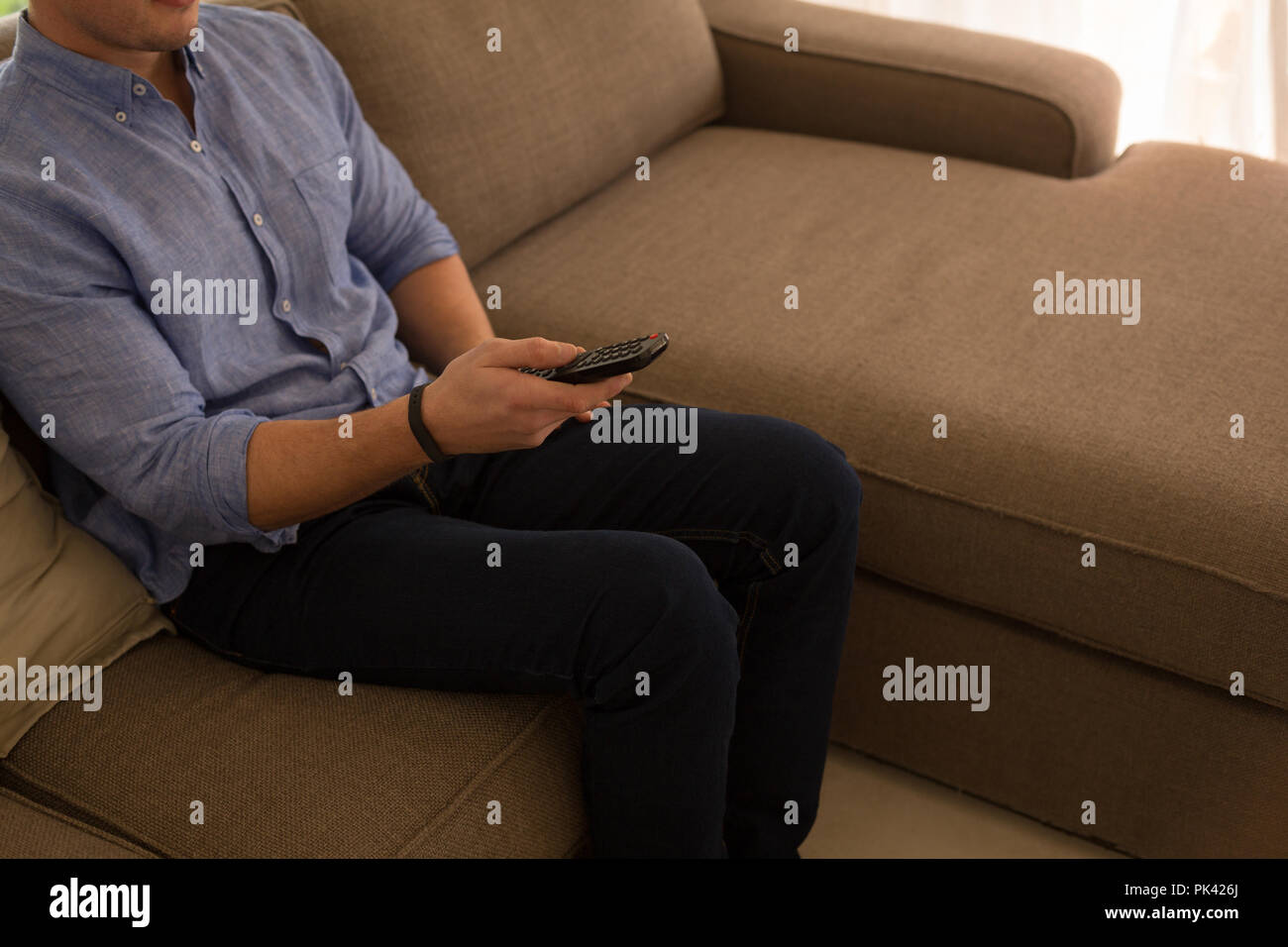 Disabled man changing channels in living room at home Stock Photo