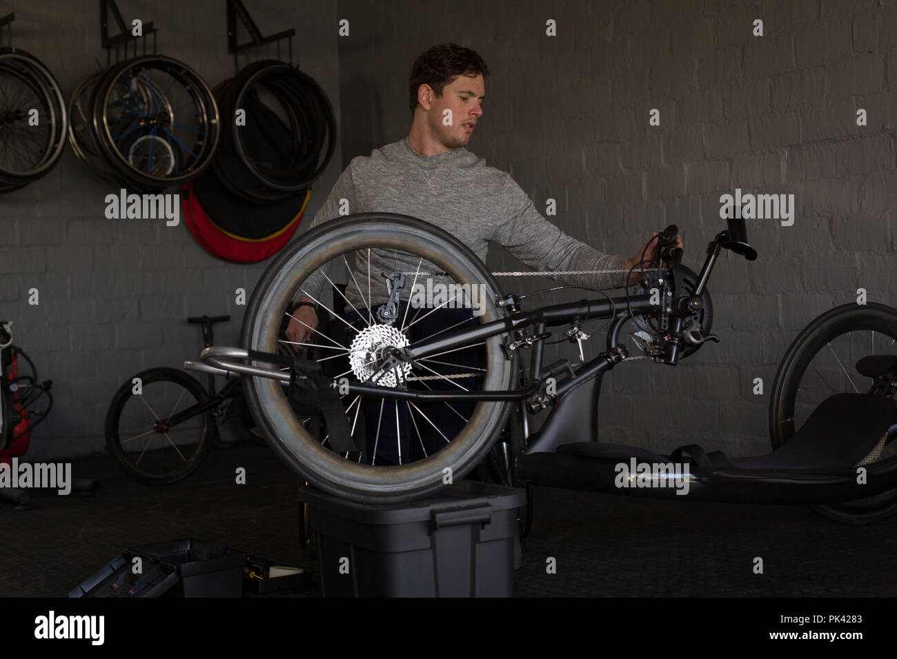 Disabled man repairing wheelchair at workshop Stock Photo