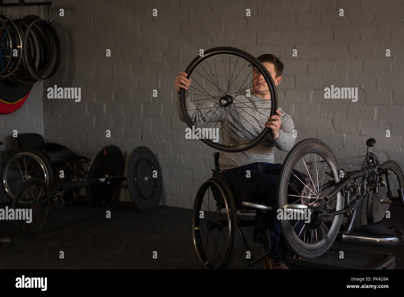Disabled man repairing wheelchair at workshop Stock Photo