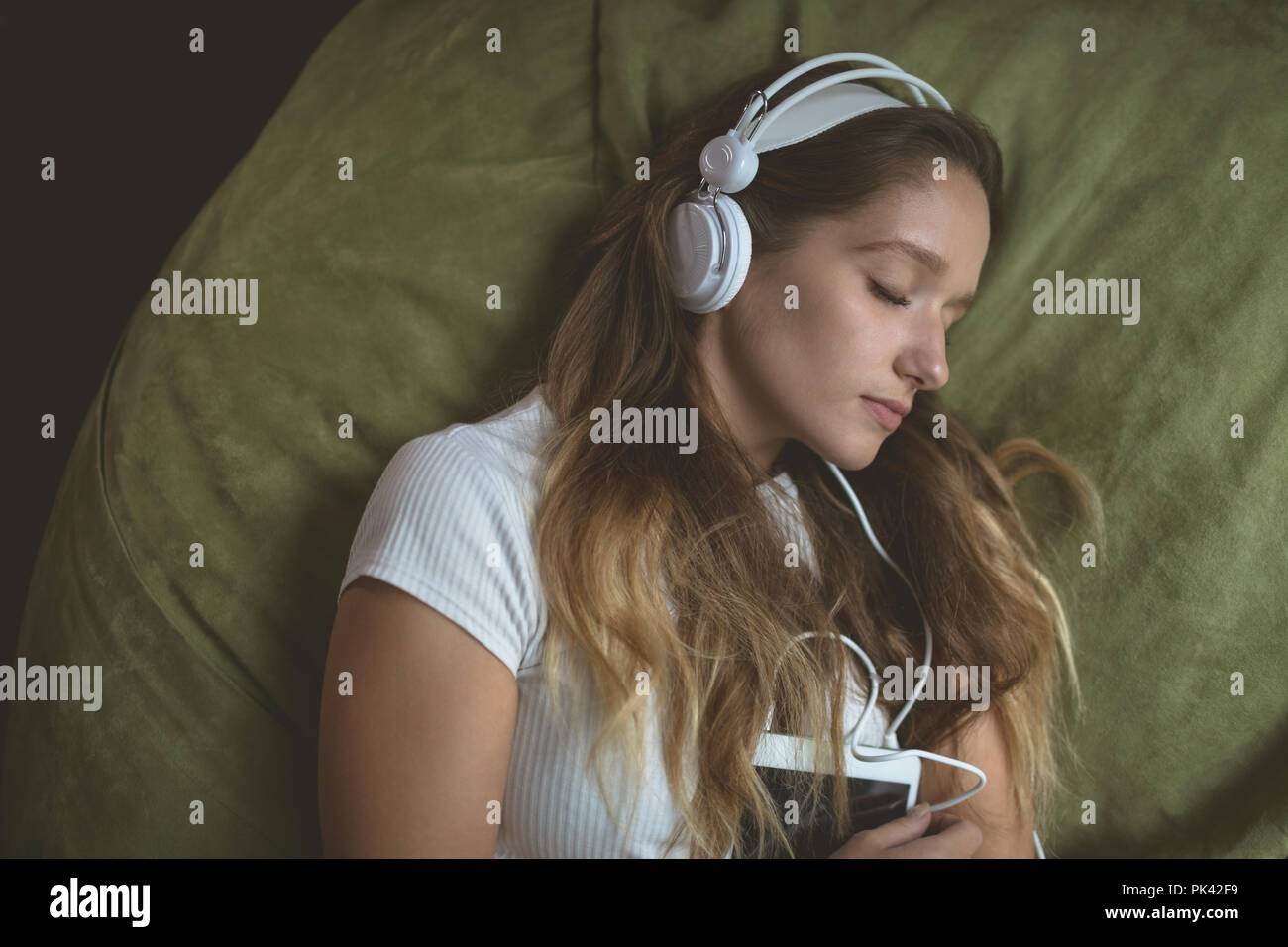 Woman listening music on headphones while sleeping Stock Photo
