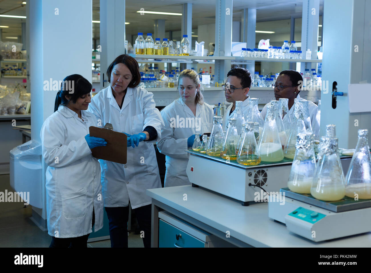 Team of scientist interacting over clipboard Stock Photo