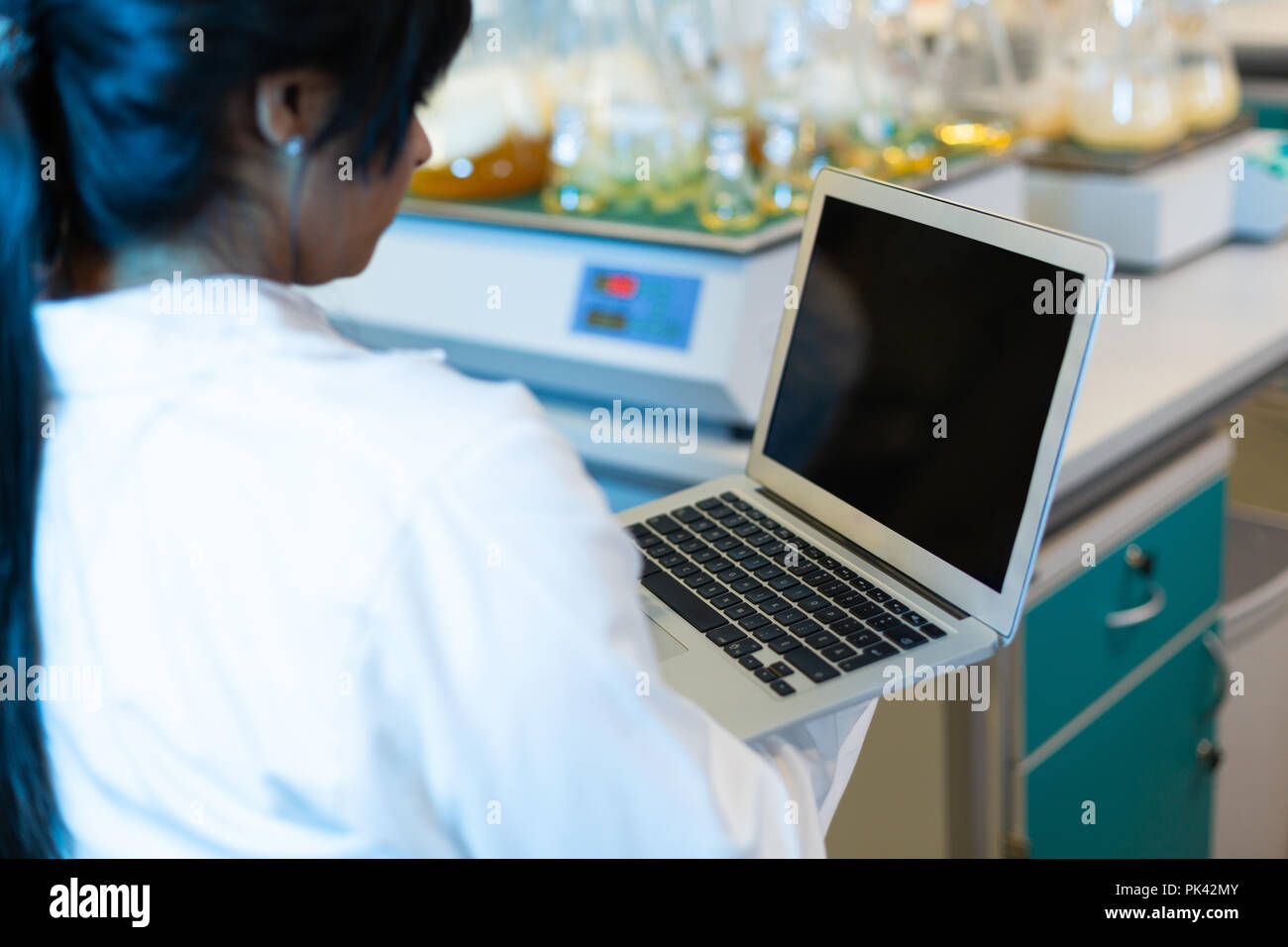 Female scientist using laptop Stock Photo