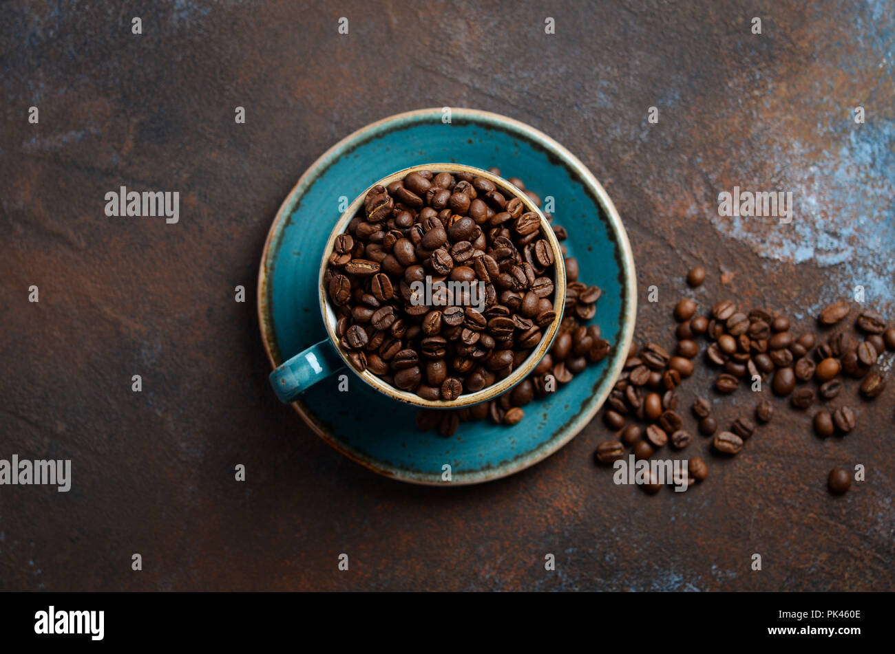 Natural organic roasted coffee beans in blue cup on dark rusty background, top view, flat lay, copy space. Stock Photo
