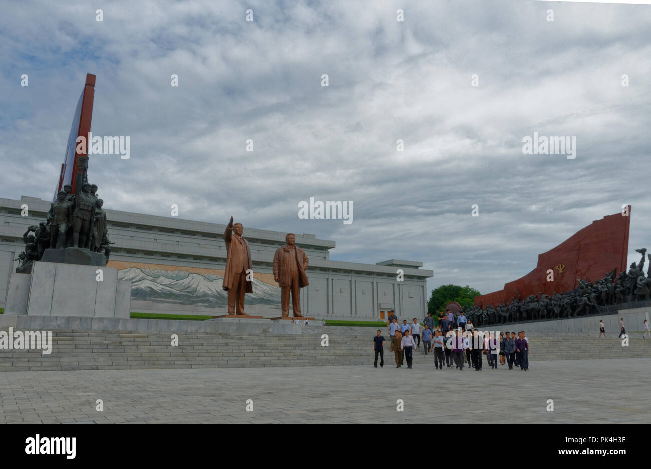 North Korea, the Mansudae Hill Grand Monument, statues of Kim Il Sung and Kim Jong Il, with mosaic of  Paekdu Mountain behind.with tourists visitors Stock Photo