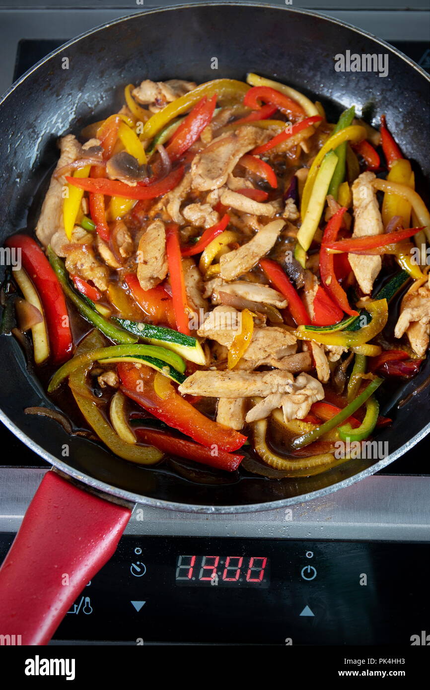 Chicken and veggies fried in pan on the electric hob Stock Photo