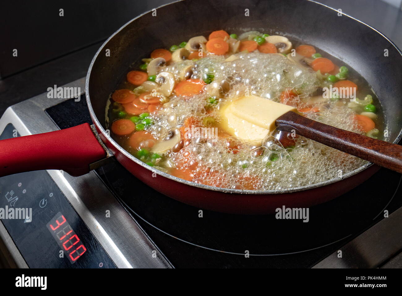 Vegetables with mushrooms cooked in a pan with a silicone spatula Stock Photo