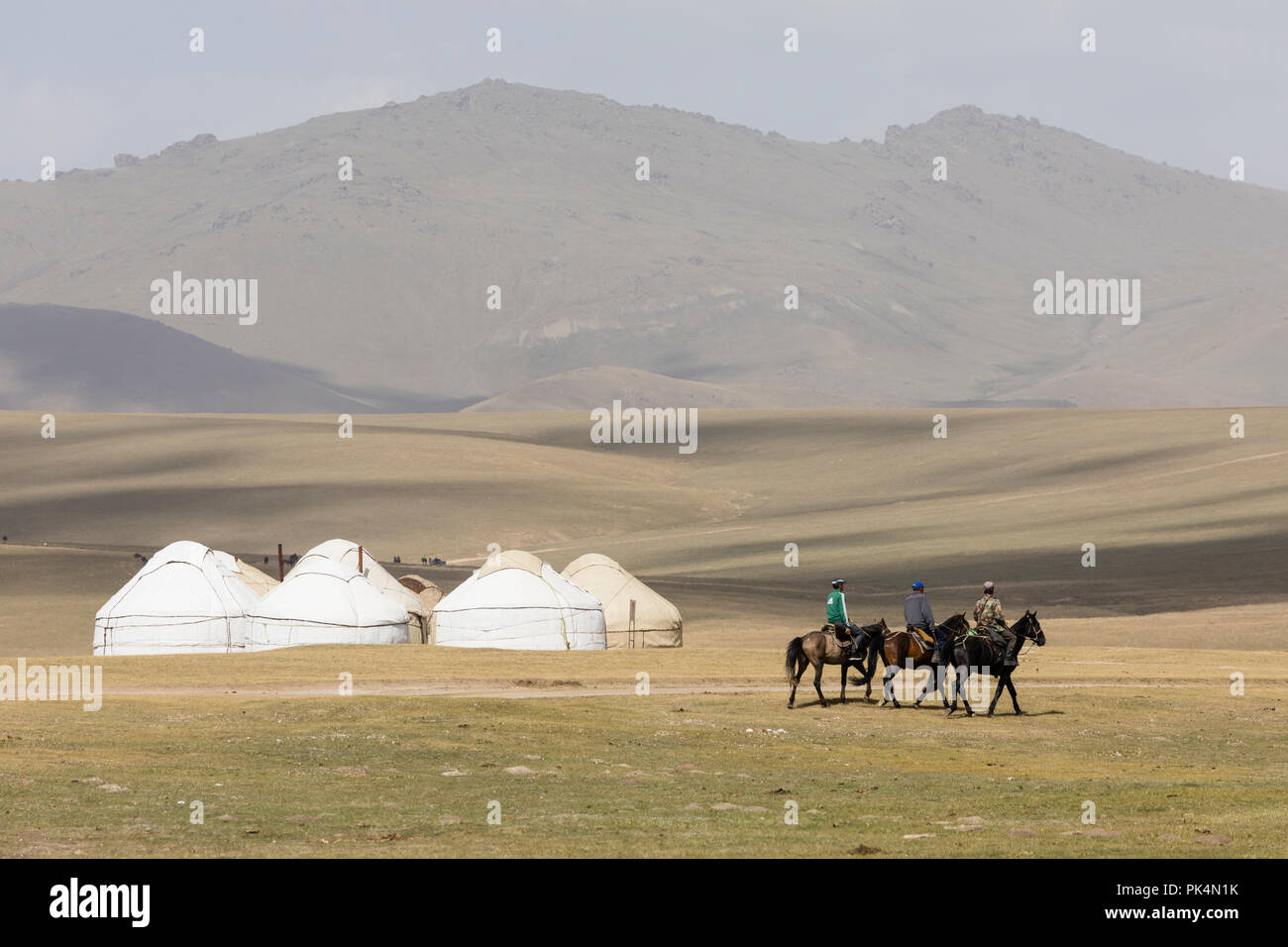 Song Kul, Kyrgyzstan, August 8 2018: Three Kyrgyz people ride their horses through the steppe at Song Kul Lake in Kyrgyzstan Stock Photo