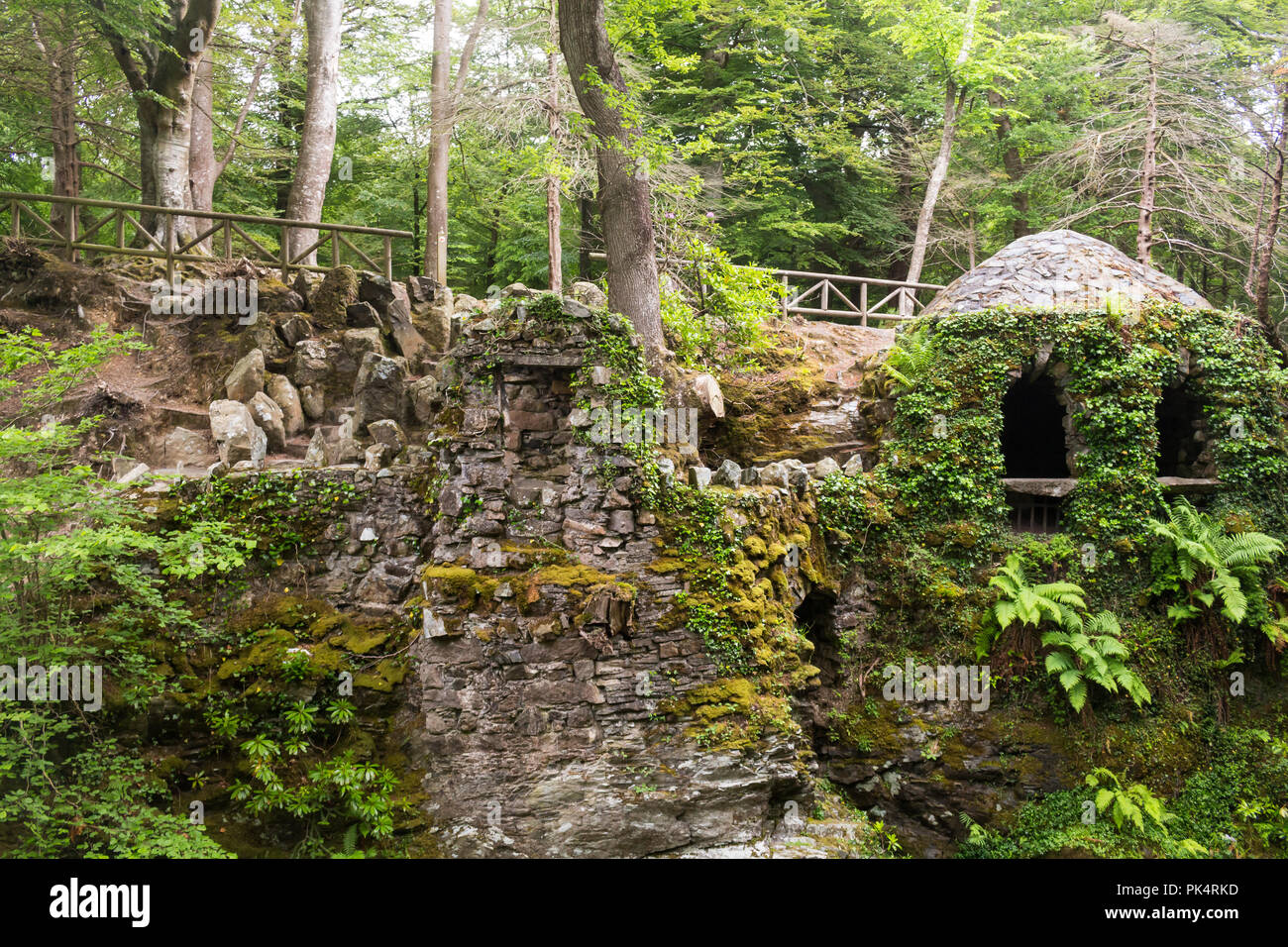 The Hermitage in Tollymore Forest Park, is a pretty  stone shelter covered in ivy on a riverwalk alongside the Shima River, Newcastle, County Down, N. Stock Photo