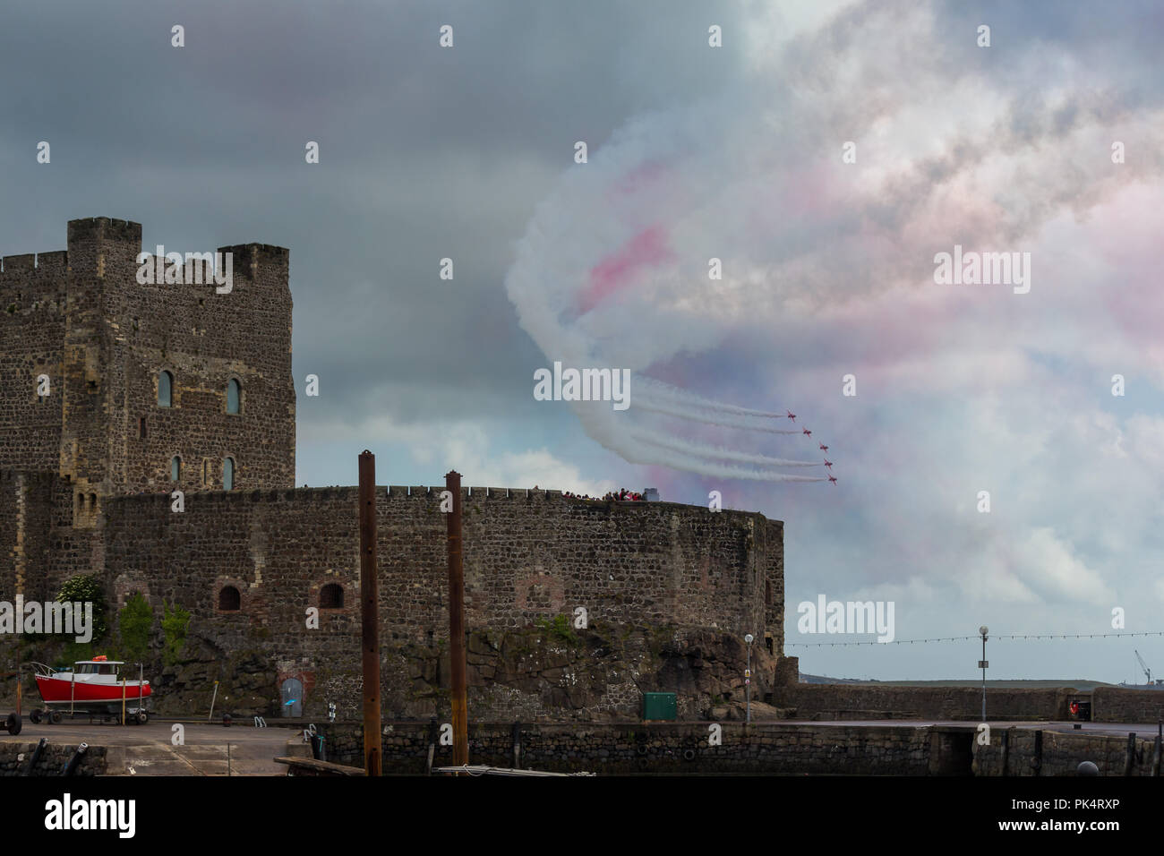 Flyby past Carrickfergus Castle - The Red Arrows, the Royal Air Force aerobatics team, on display at airshow over Carrickfergus Castle, County Antrim, Stock Photo