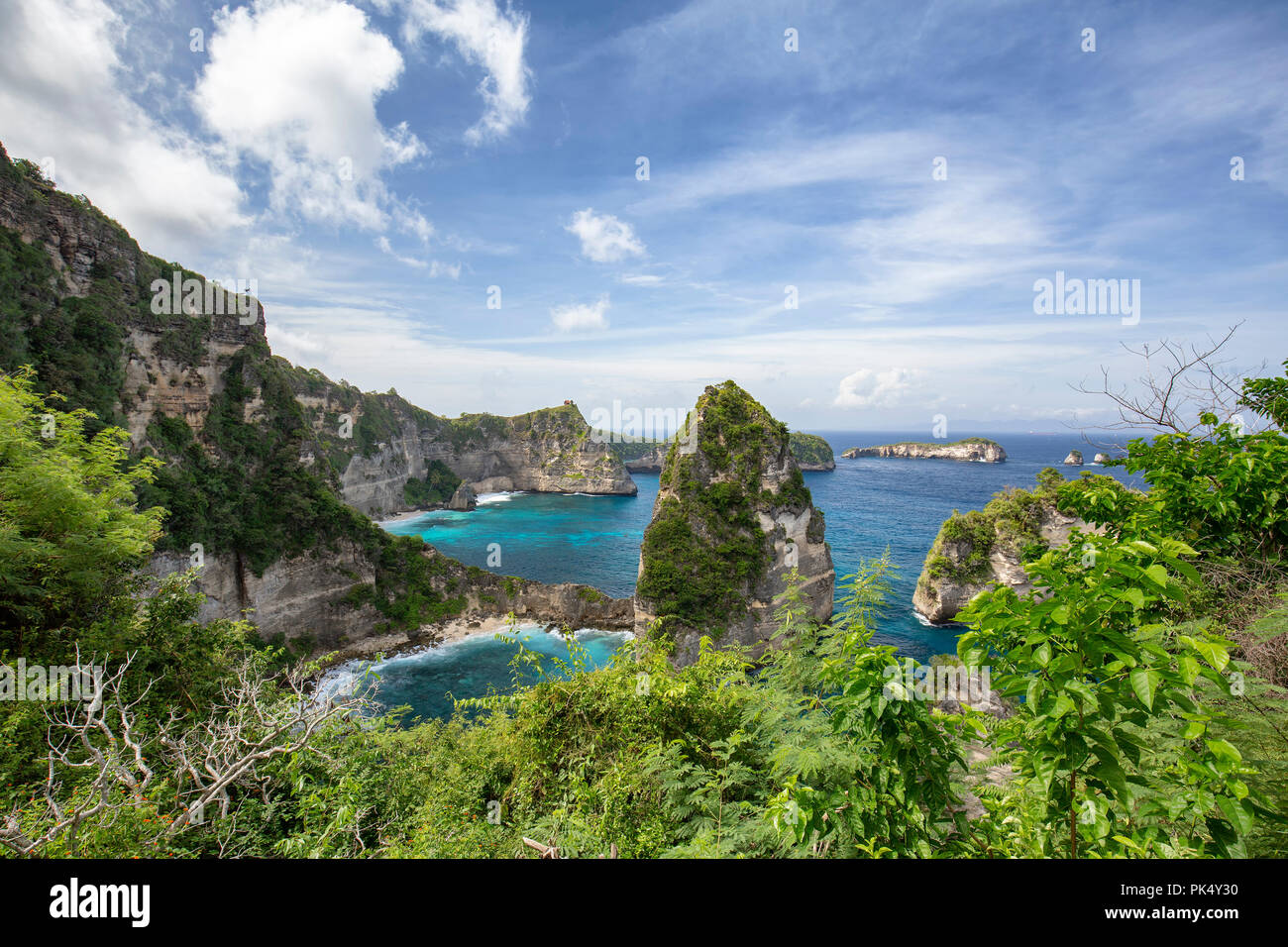 Tropical plants frame the Raja Lima islands in the distance on Nusa Penida, Indonesia. Stock Photo