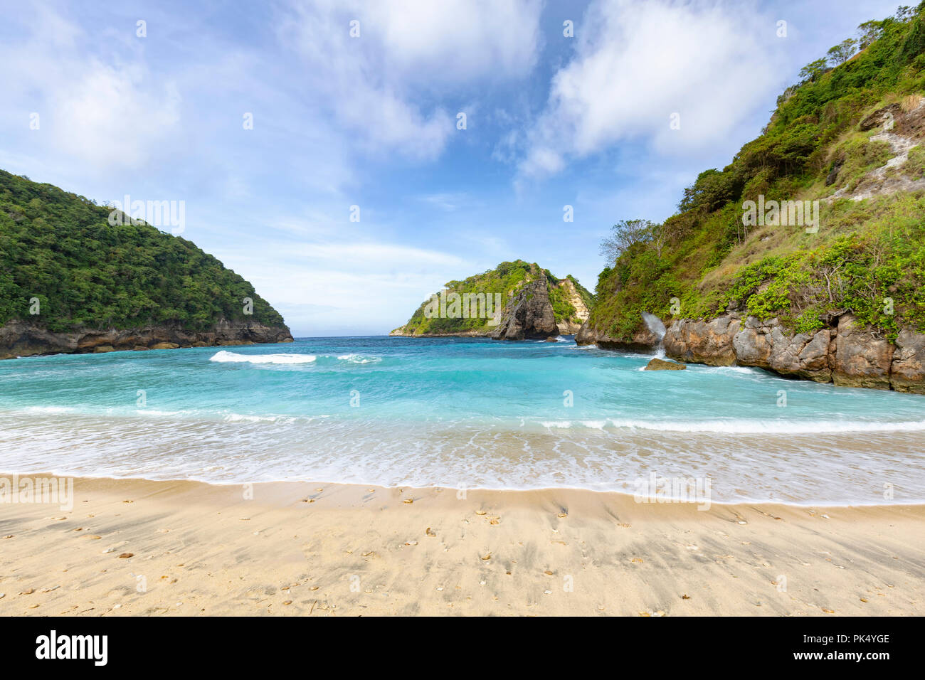 A wide angle view of the surf slowly breaking on Atuh Beach in Nusa Penida in Indonesia. Stock Photo
