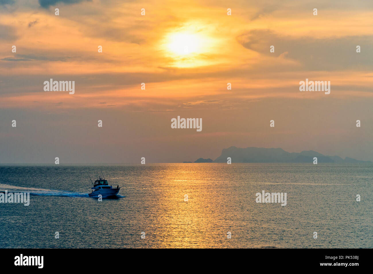 Speedboat for fishing on the sea returning to shore during the sunset in the midst of nature and the beautiful sky. Stock Photo