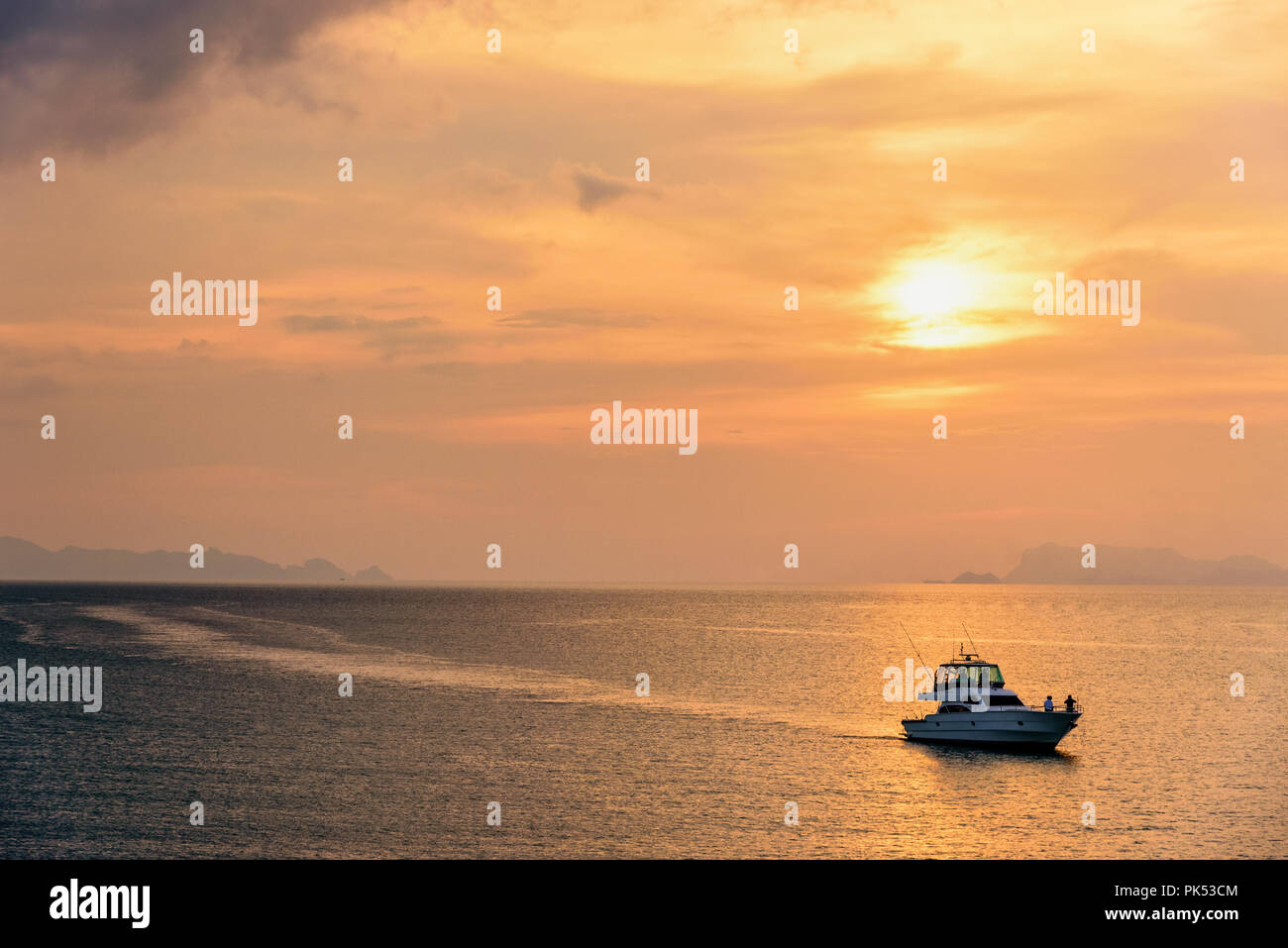 Speedboat for fishing on the sea returning to shore during the sunset in the midst of nature and the beautiful sky. Stock Photo
