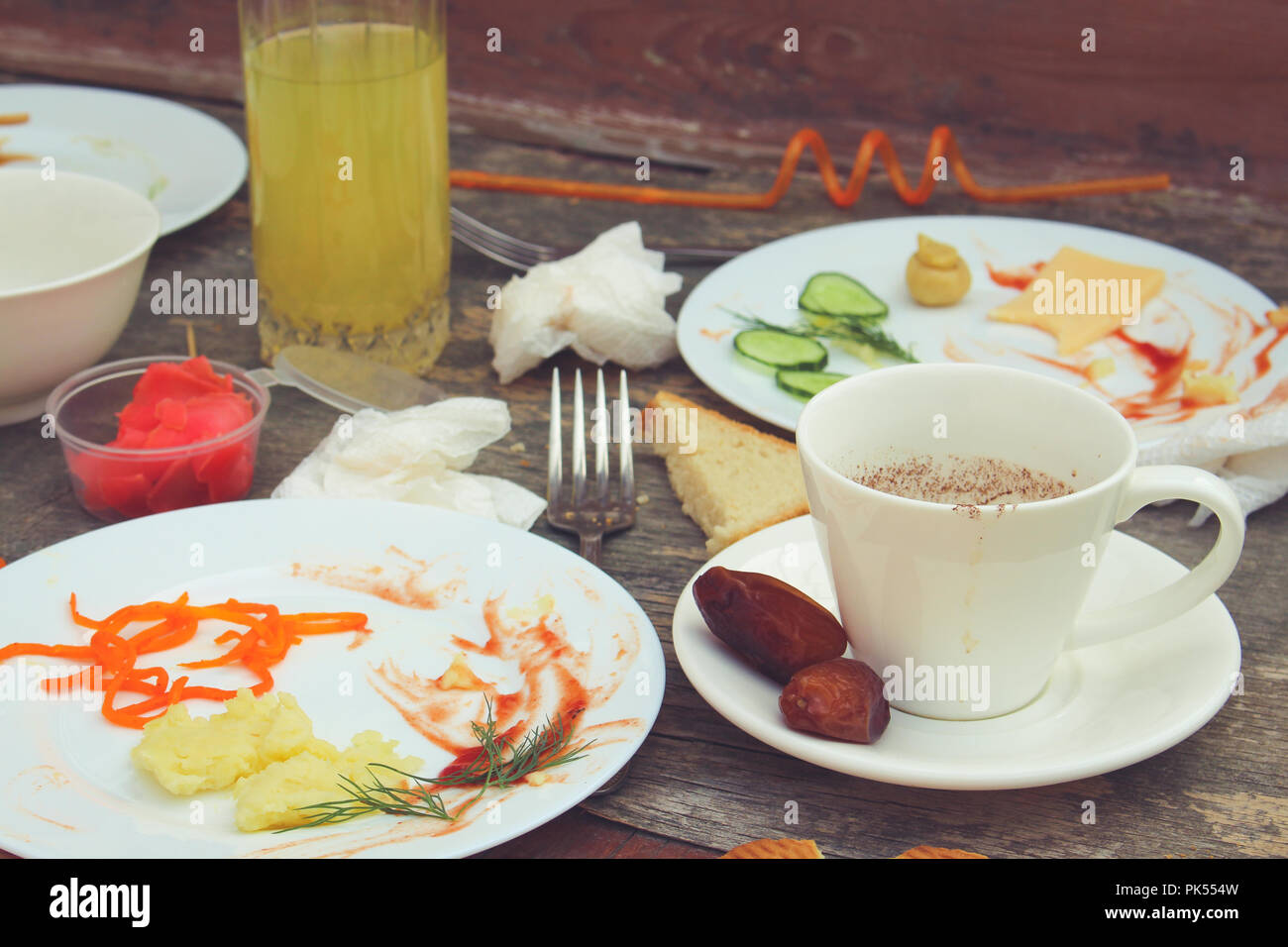 Messy table after party. Leftover food, spilled drinks, dirty dishes. Toned image. Stock Photo
