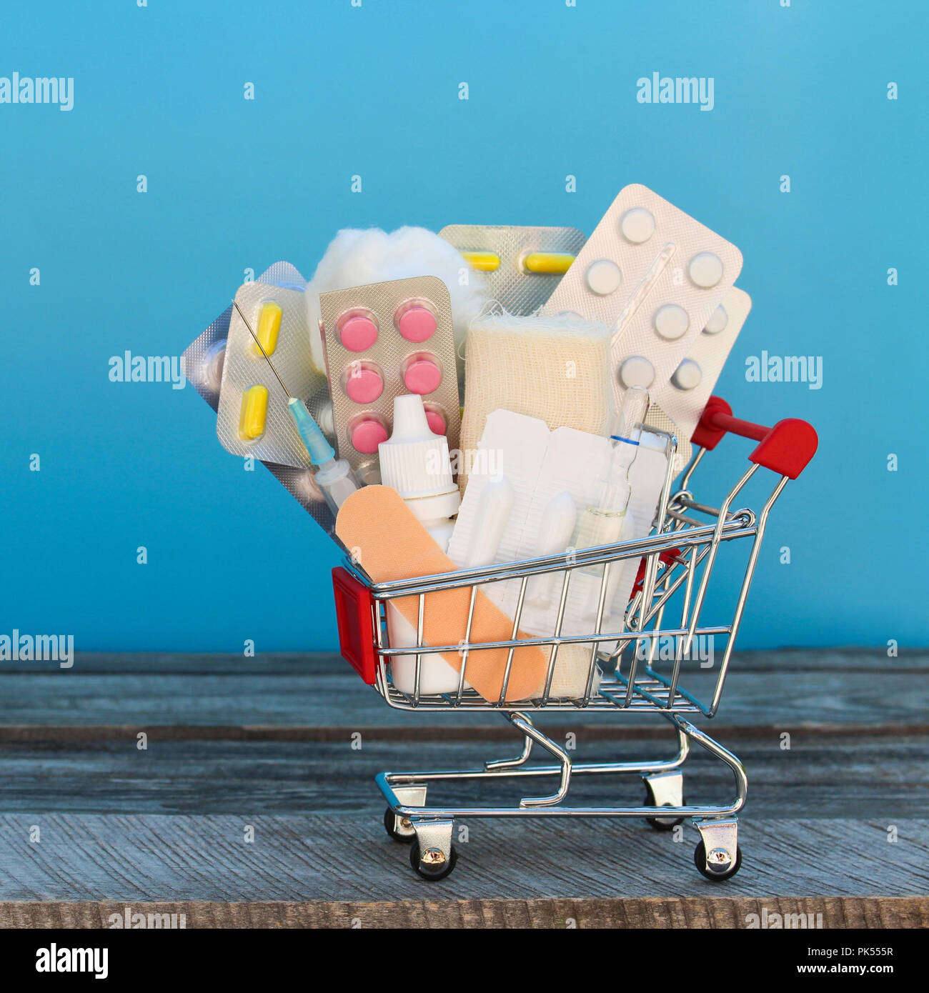 Shopping cart with medication on a blue background. Stock Photo