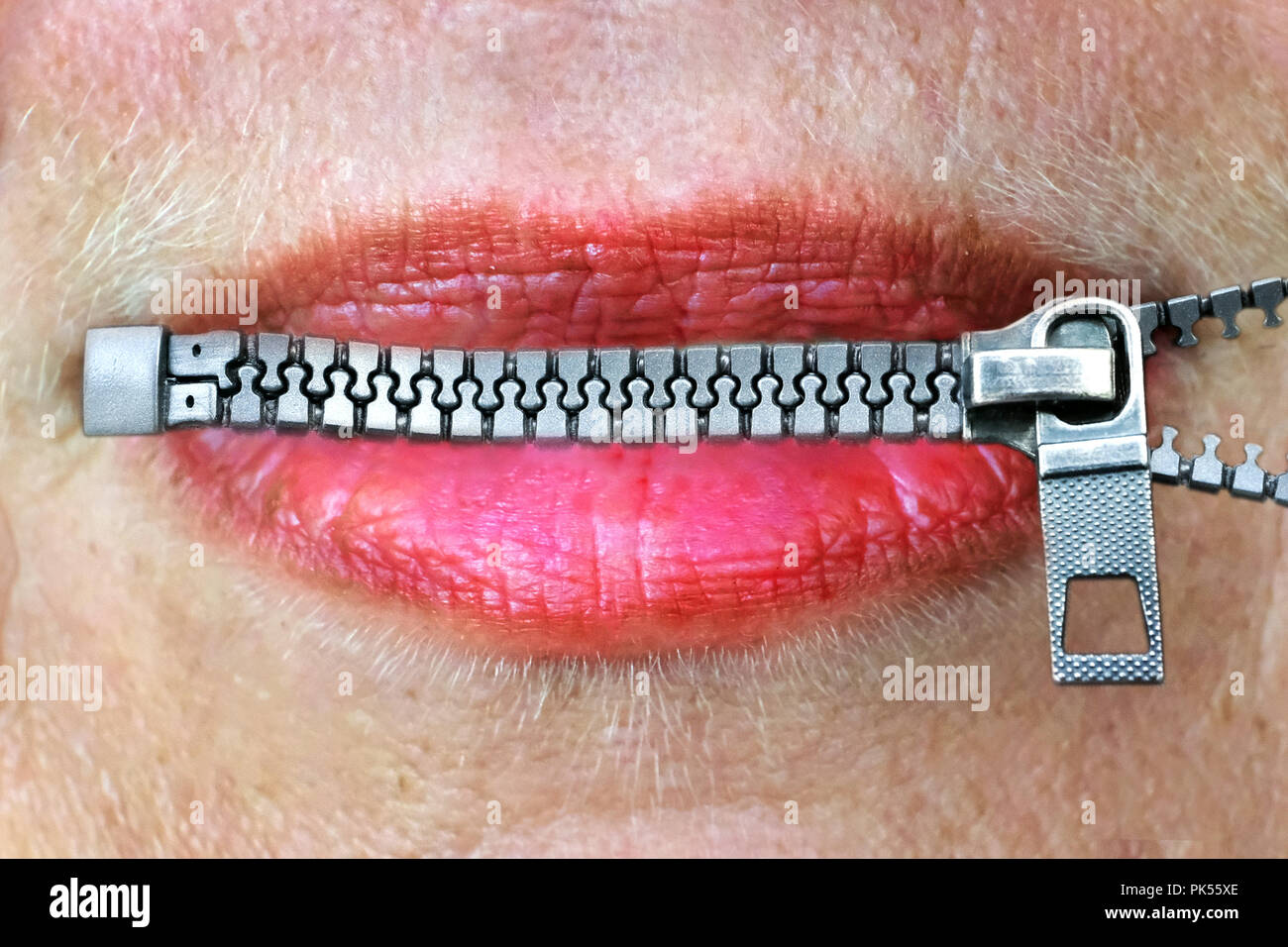 Female lips closed by zipper., symbolic photo, photomontage:   ---  Symbolfoto, Fotomontage: Weibliche Lippen durch Reißverschluß verschlossen. Stock Photo