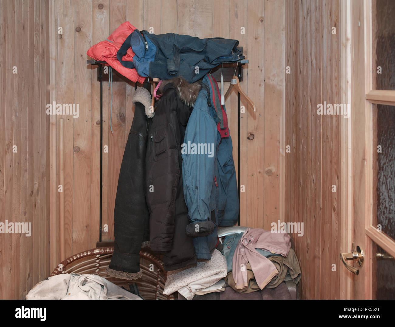 Coats and jackets hanging on a rack in a messy room Stock Photo Alamy