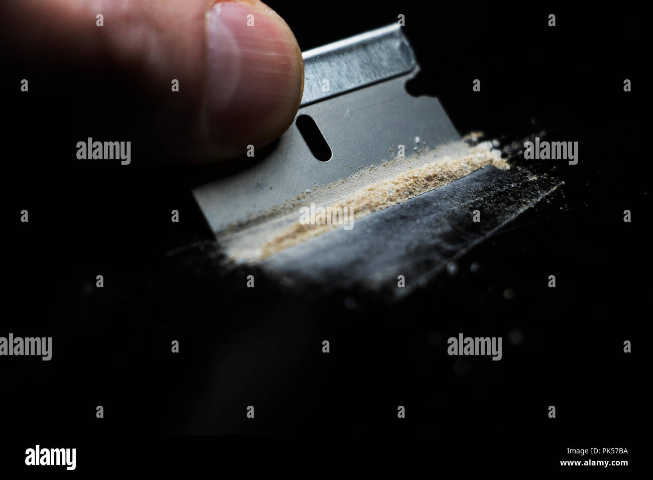 Razor blade and powered Drugs cut up on a black table. Cutting lines. Stock Photo