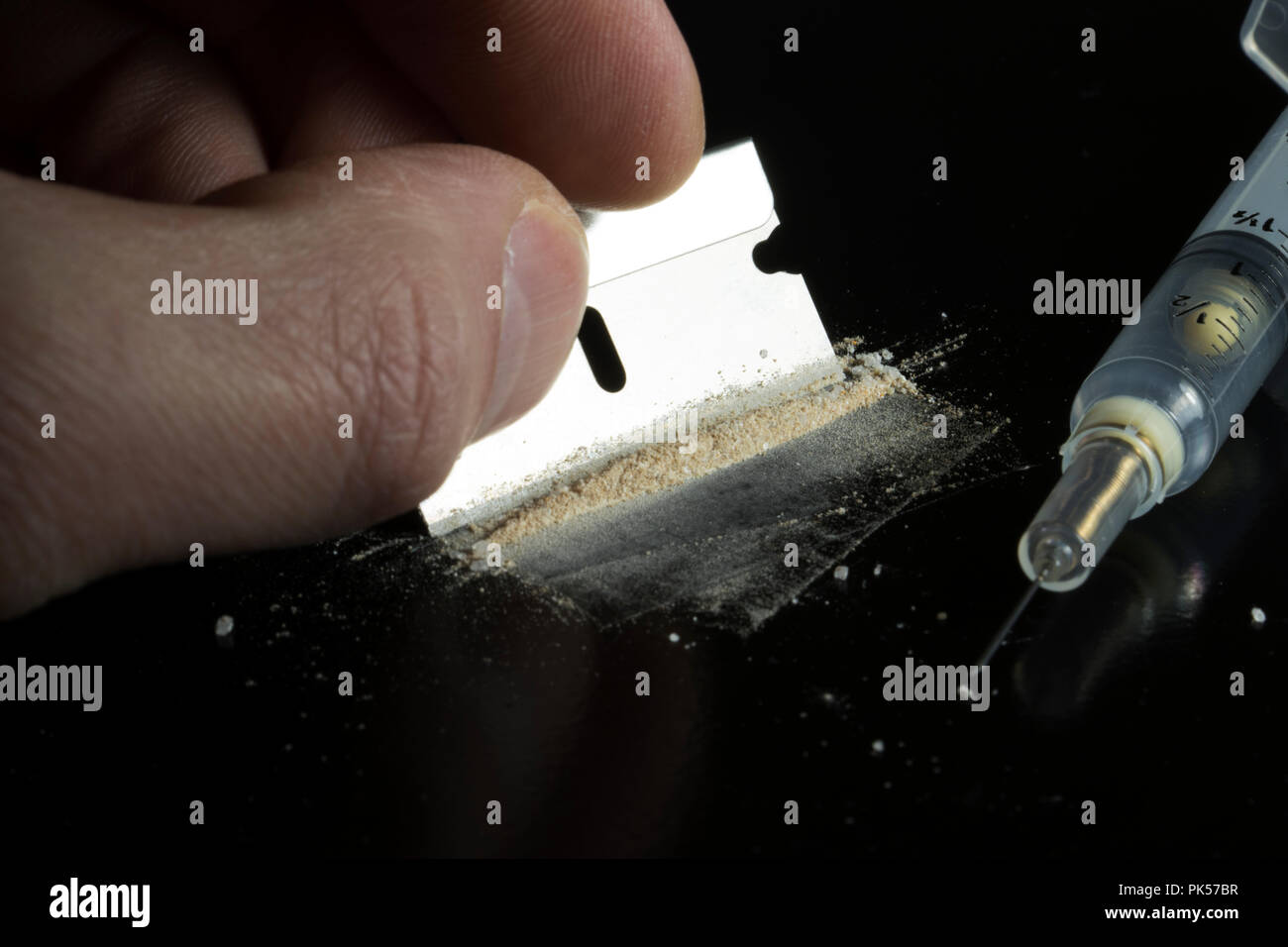 Holding a razor blade with a disposable syringe isolated on a black