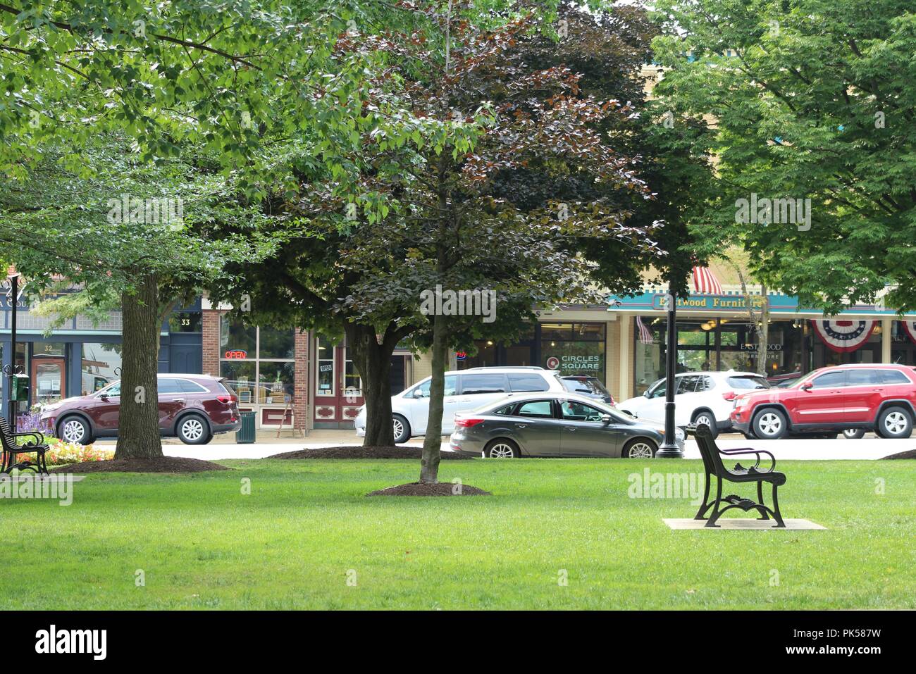 store front view from town square park with traffic flowing on busy street Stock Photo