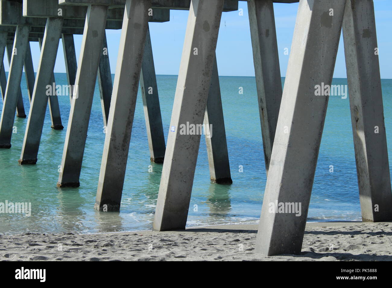 underneath concrete pier showing the pillars and the ocean Stock Photo