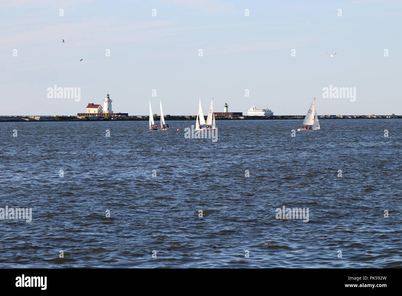 lighthouses out on a lake with sail boats and ship in the water Stock Photo