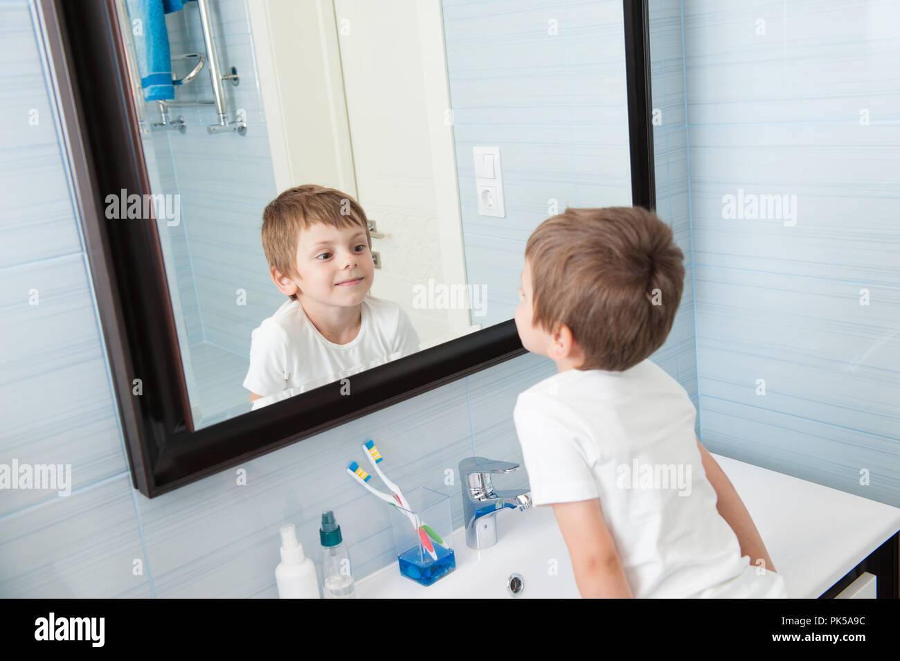 cute-healthy-caucasian-small-kid-watching-at-himself-in-mirror-in-blue