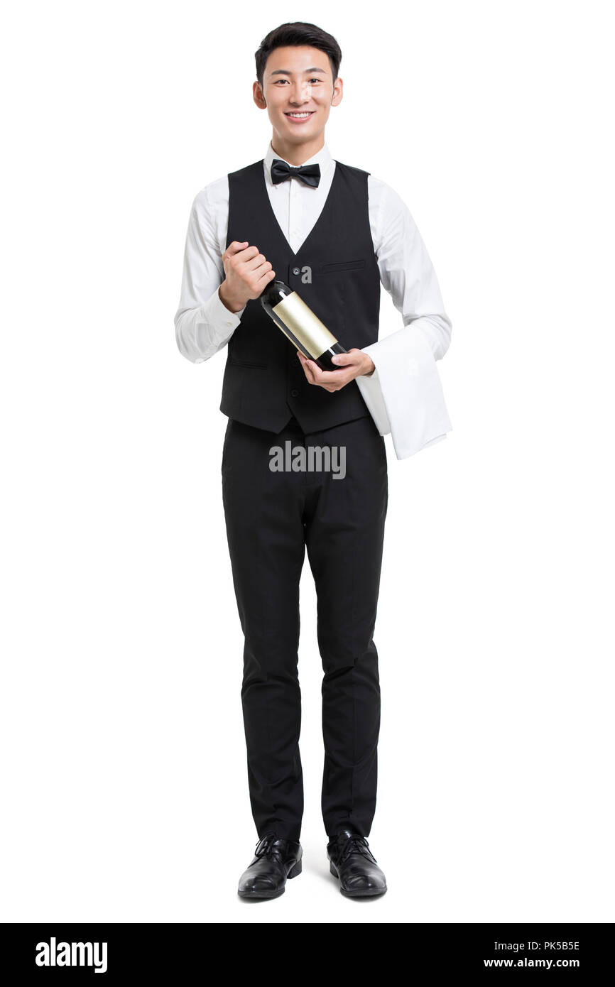 Cheerful young Chinese waiter holding a bottle of red wine Stock Photo