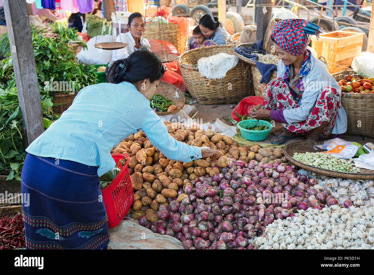 A client select the goods from a vegetable stand in a market. Bagan, Myanmar (Burma). Stock Photo