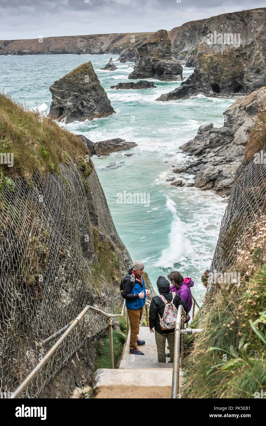 Walkers standing on the steps at the entrance leading down to Bedruthan Steps in Cornwall. Stock Photo