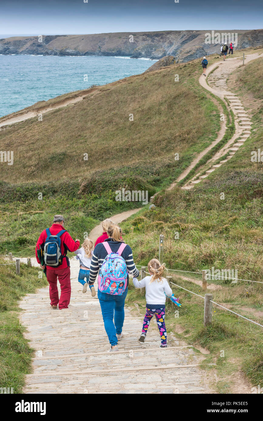 A family of holidaymakers walking down the South West Coast Path to Bedruthan Steps in Cornwall. Stock Photo