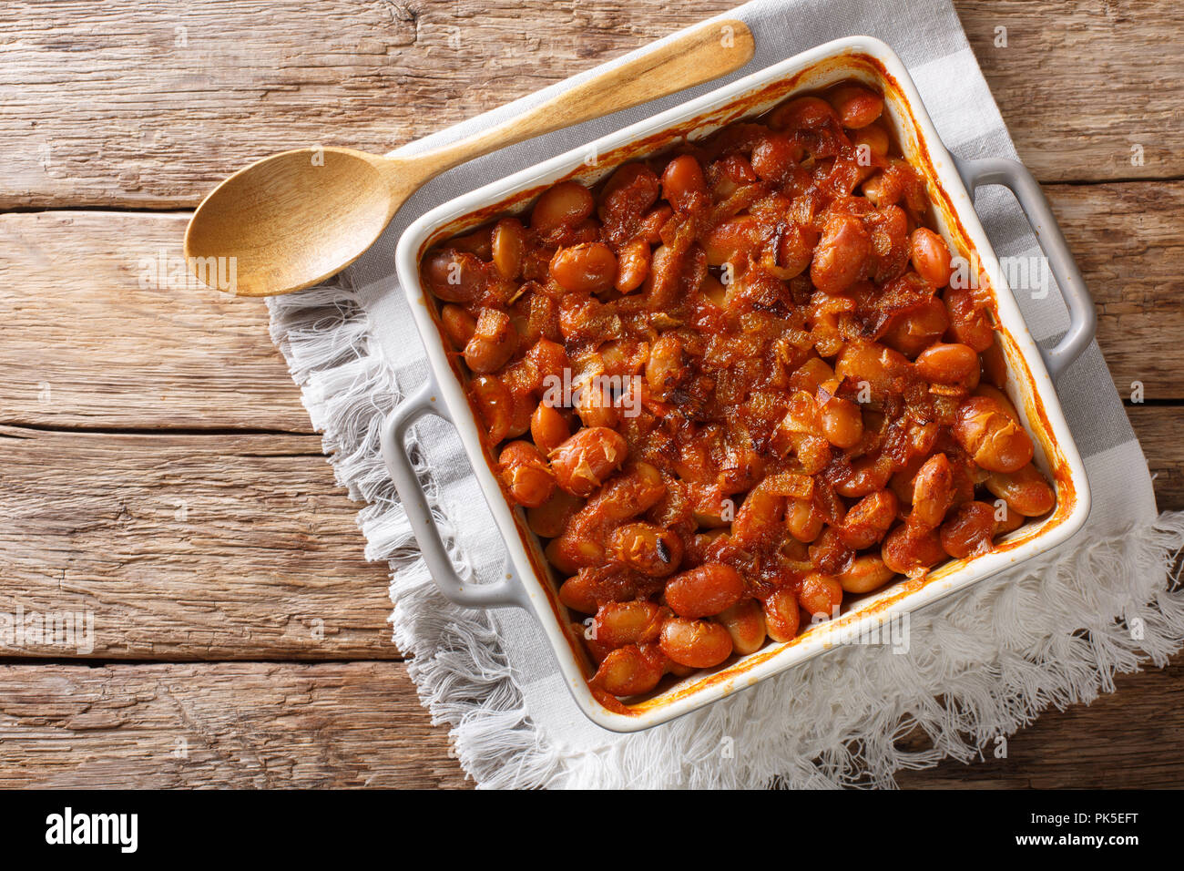 Baked spicy beans prebranac close-up in a baking dish on a table. horizontal top view from above Stock Photo