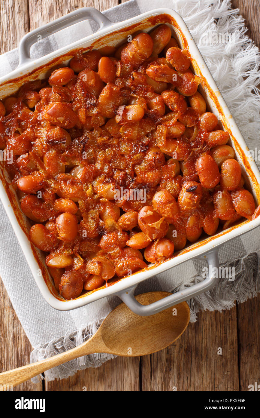Baked spicy beans prebranac close-up in a baking dish on a table. Vertical top view from above Stock Photo