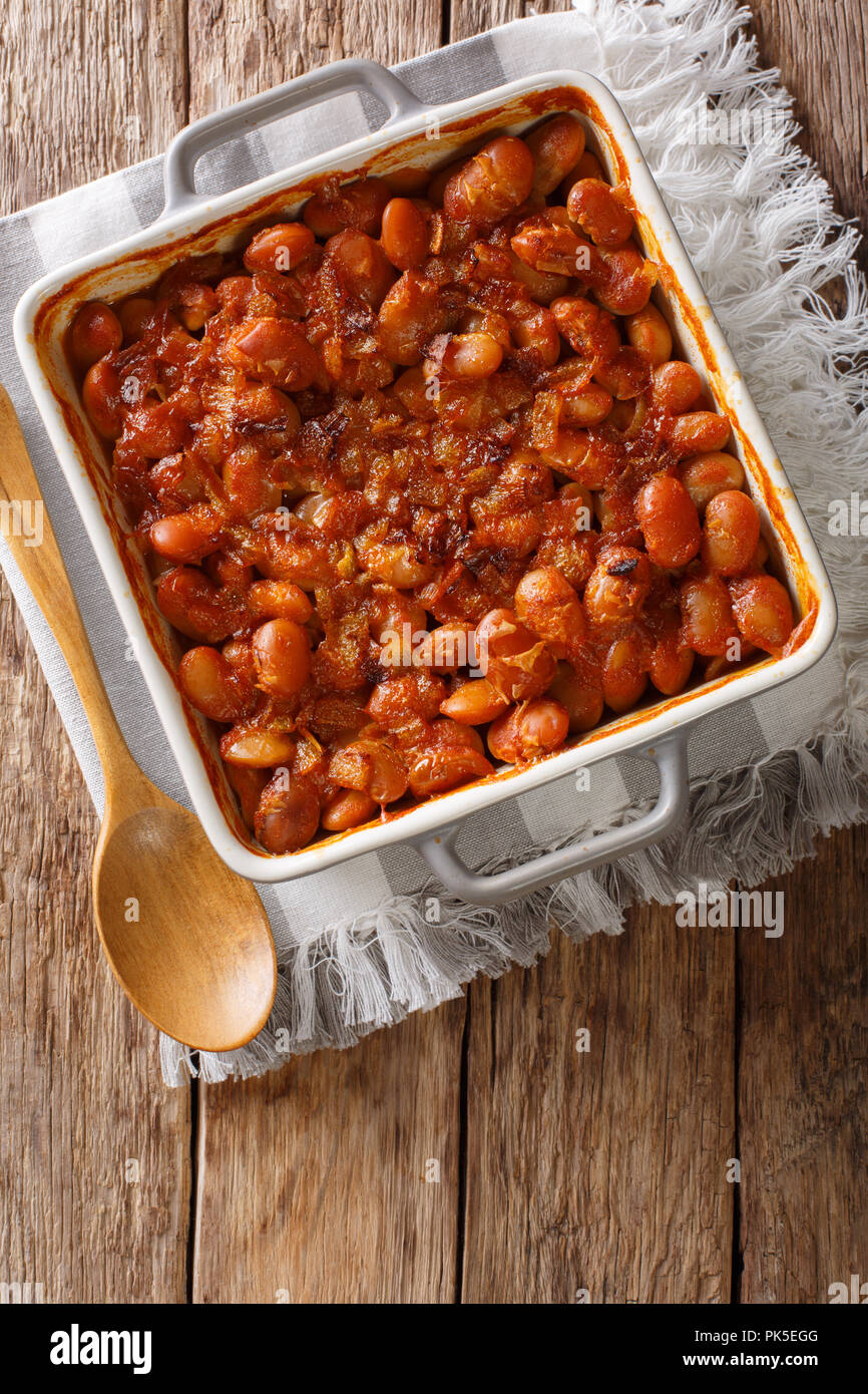 Delicious prebranac baked beans with onions close-up in a baking dish on a table. Vertical top view from above Stock Photo