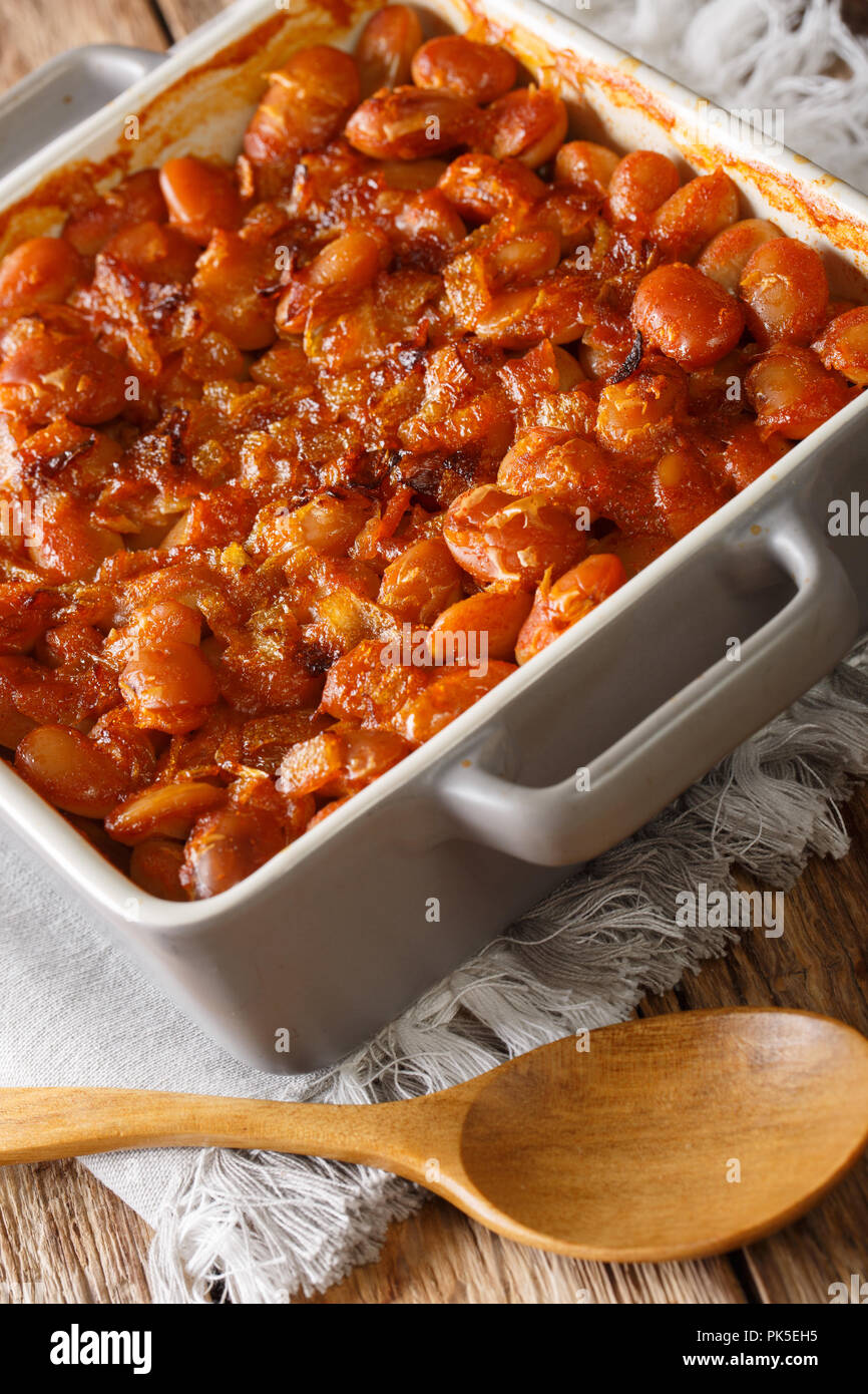Baked spicy beans prebranac close-up in a baking dish on a table. vertical Stock Photo