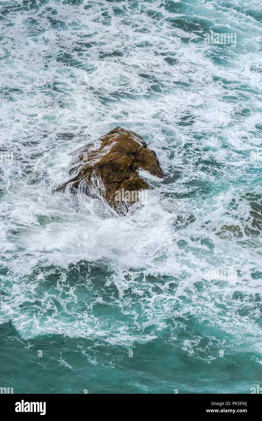 Choppy sea swirling around a rock.; Stock Photo