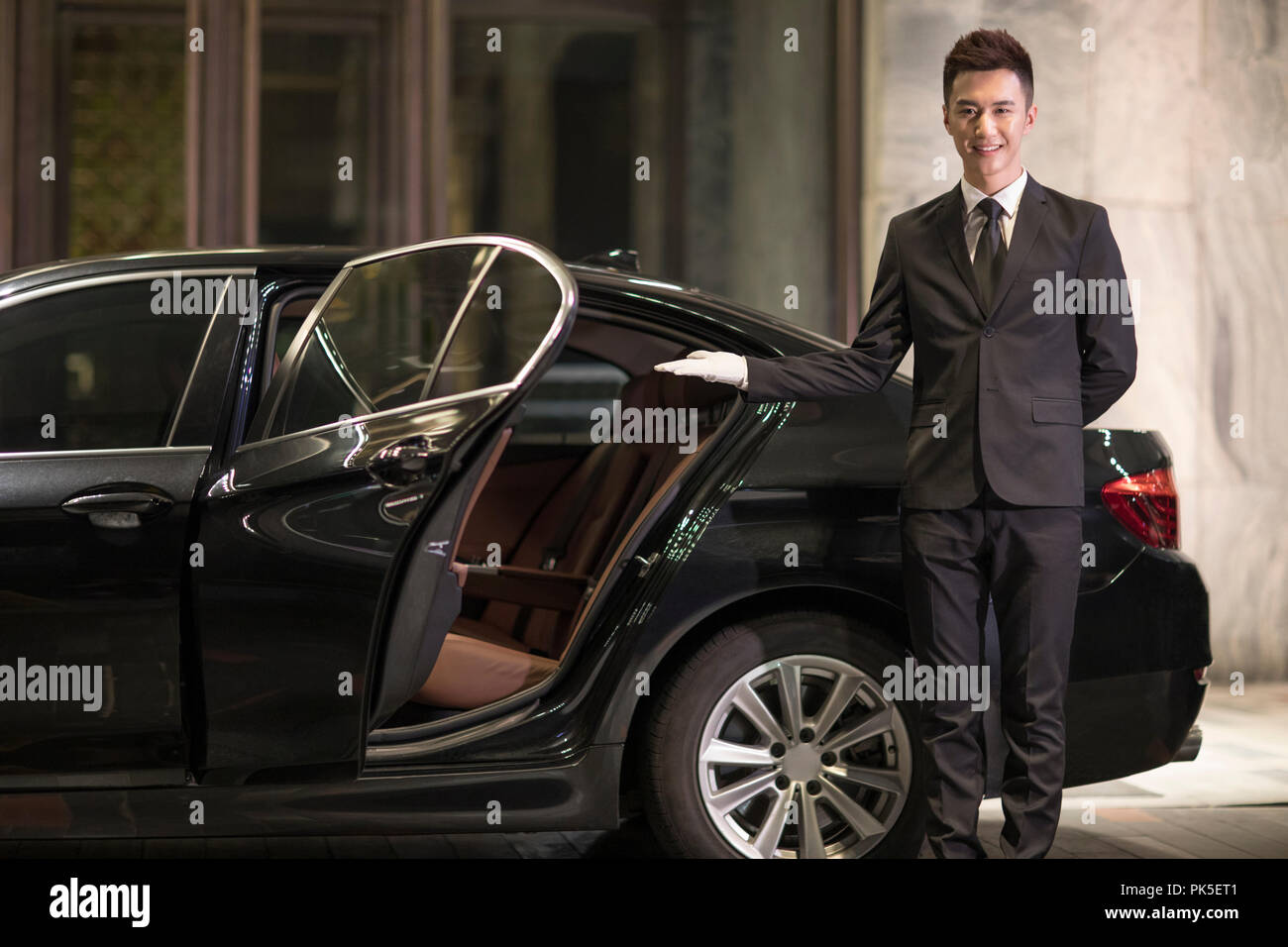 Chauffeur opening car door for passenger Stock Photo Alamy