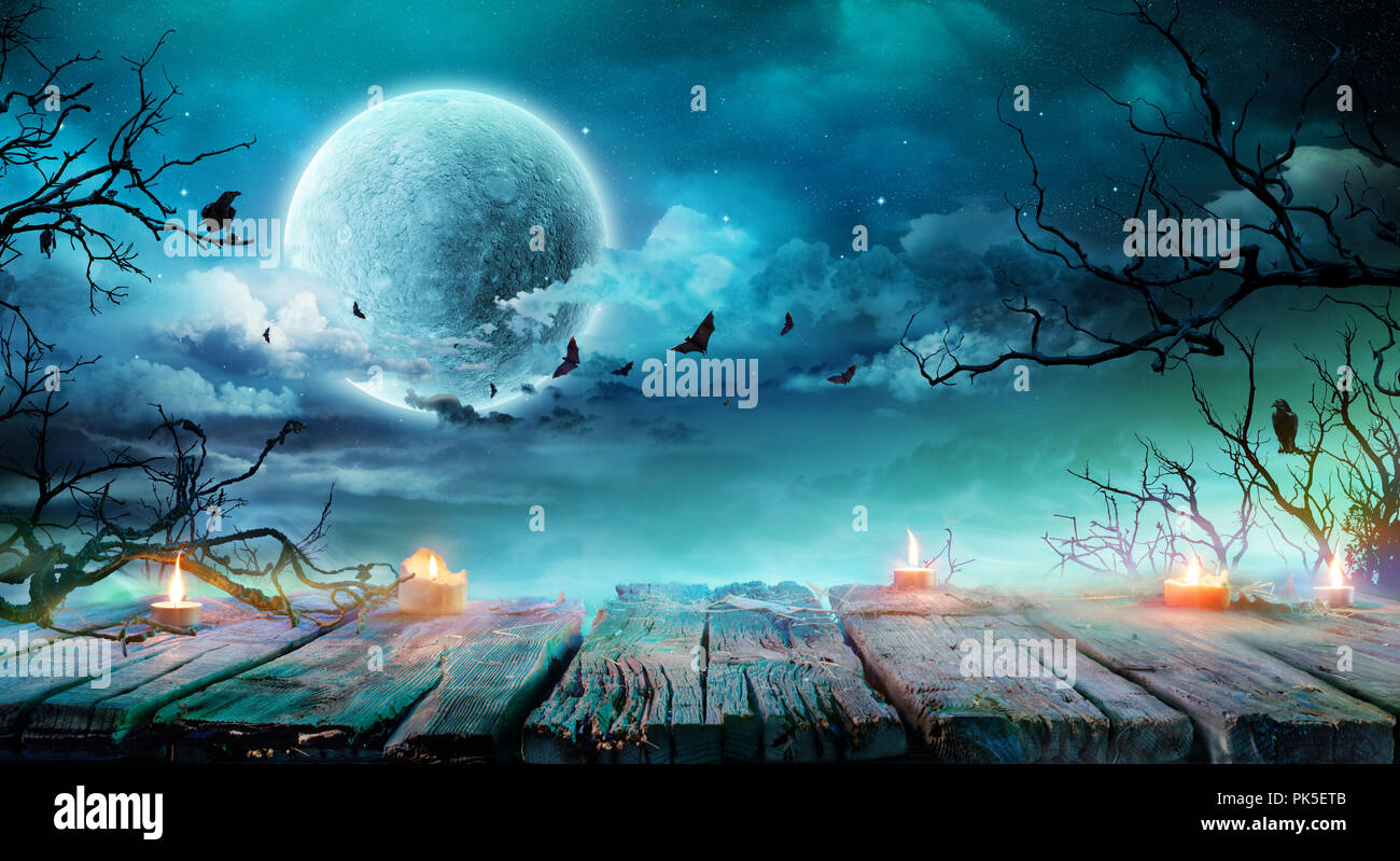 Halloween Background - Old Table With Candles And Branches At Spooky Night With Full Moon Stock Photo