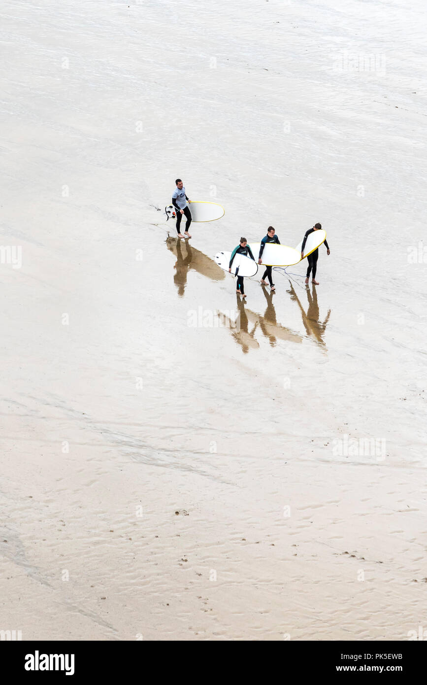 An overhead view of surfers and their surfing instructor carrying their