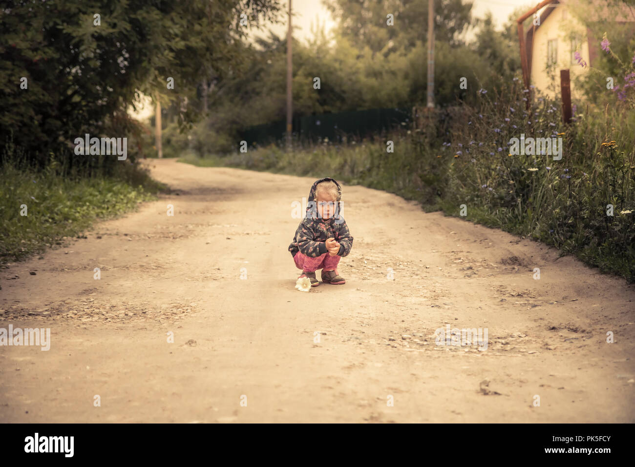 Lonely lost kid girl on rural road in countryside concept carefree childhood in countryside rustic lifestyle Stock Photo