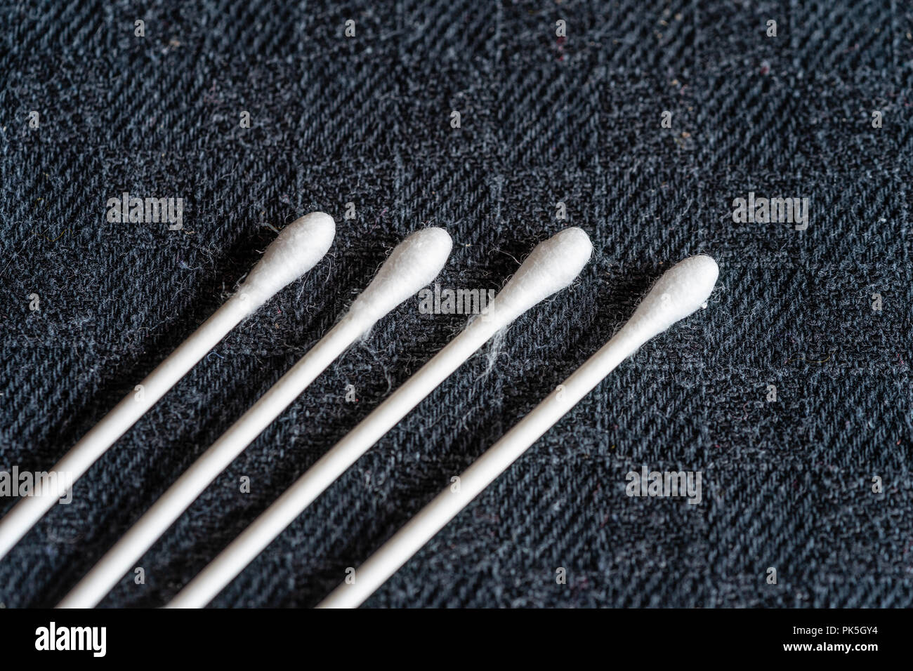 Close up of four environmentally friendly paper stemmed cotton buds against black background Stock Photo