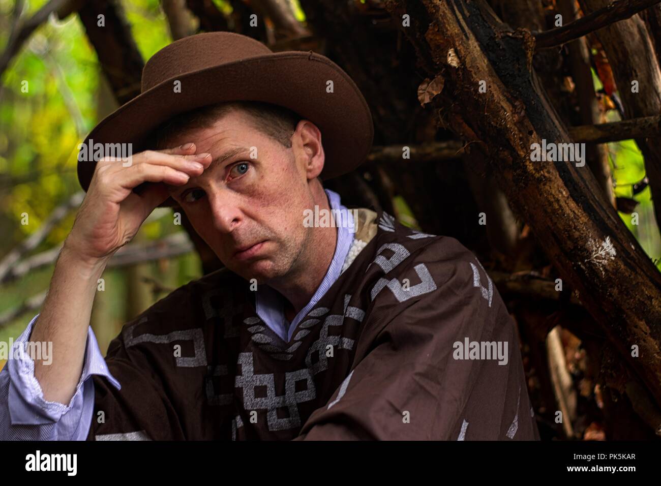 A middle aged man sits having a cigarette in a forest environment Stock Photo