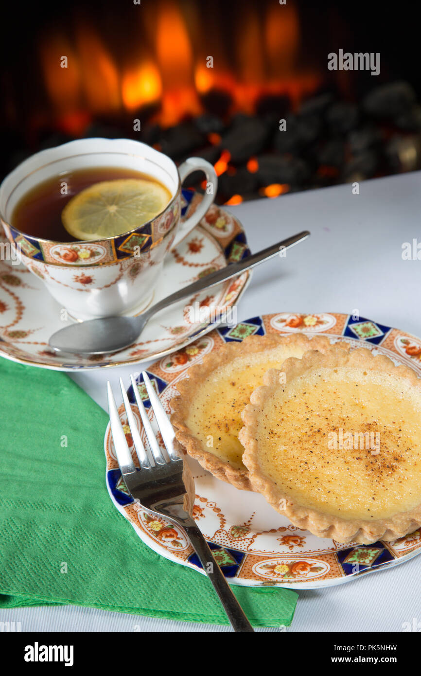 An English high tea of homemade Custard tart with lemon tea served on Roslyn bone China 8508 tea service Stock Photo