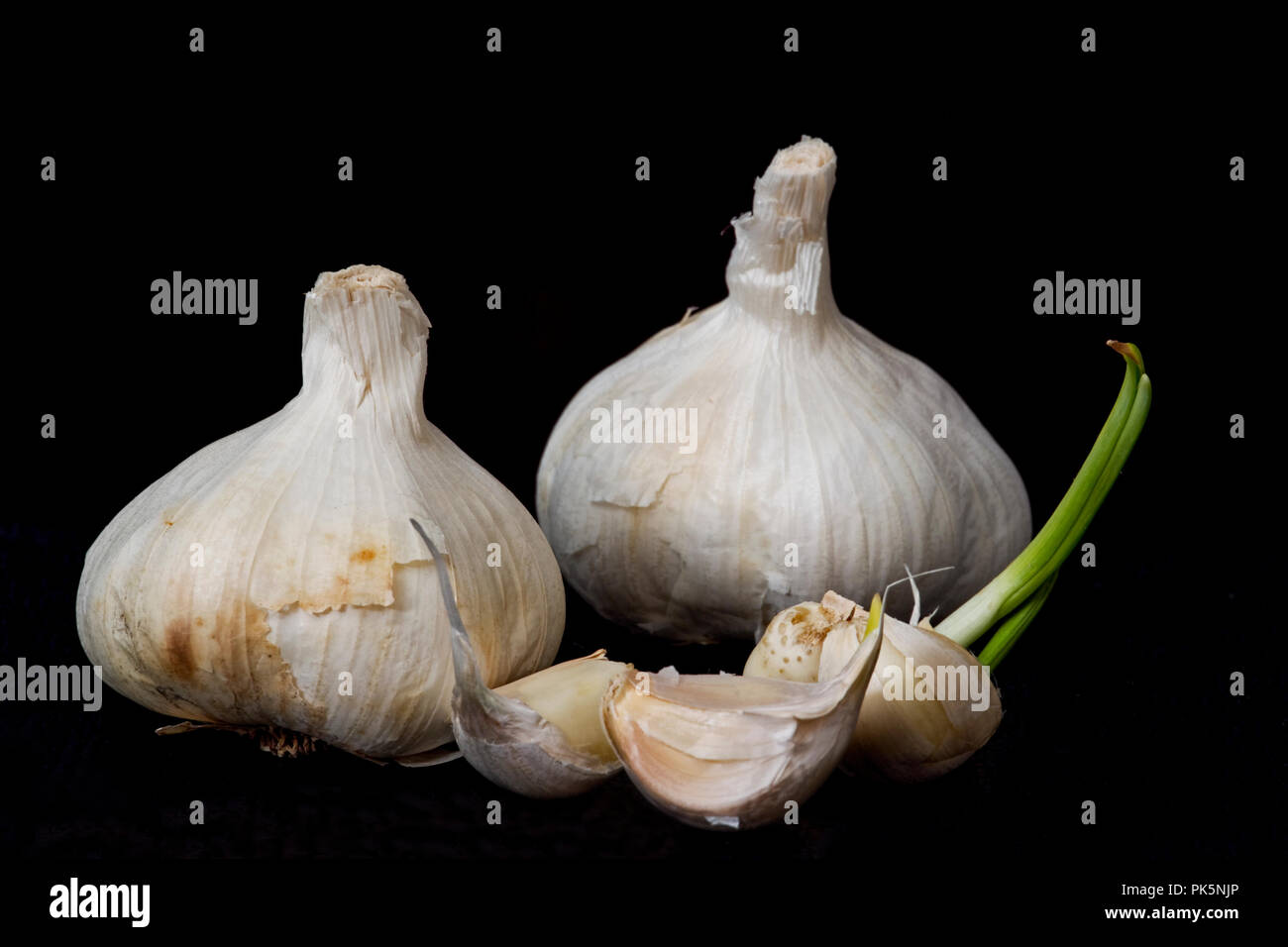 Garlic clusters and cloves closeup isolated on black background. Stock Photo