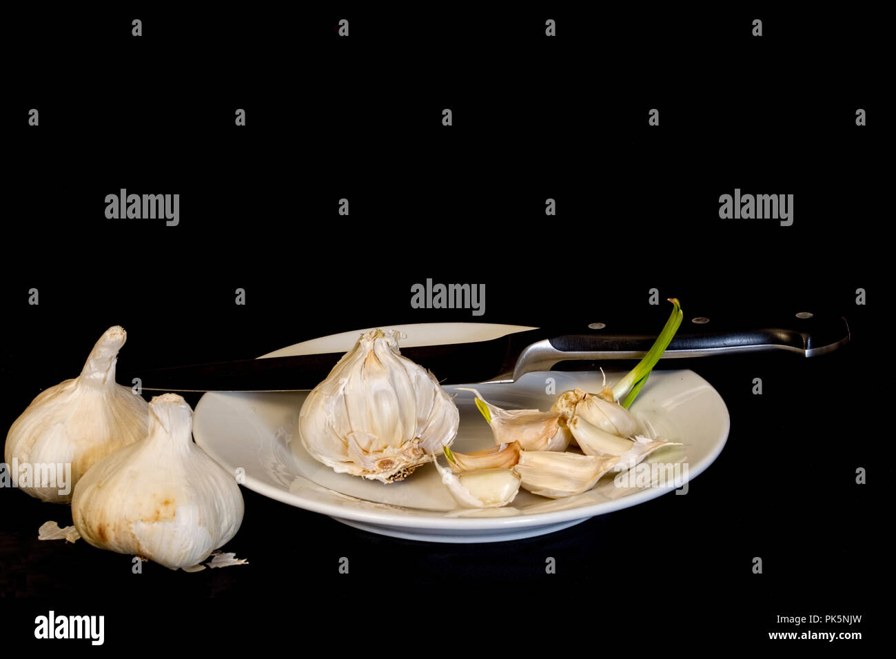 Garlic clusters and cloves closeup isolated on black background. Stock Photo
