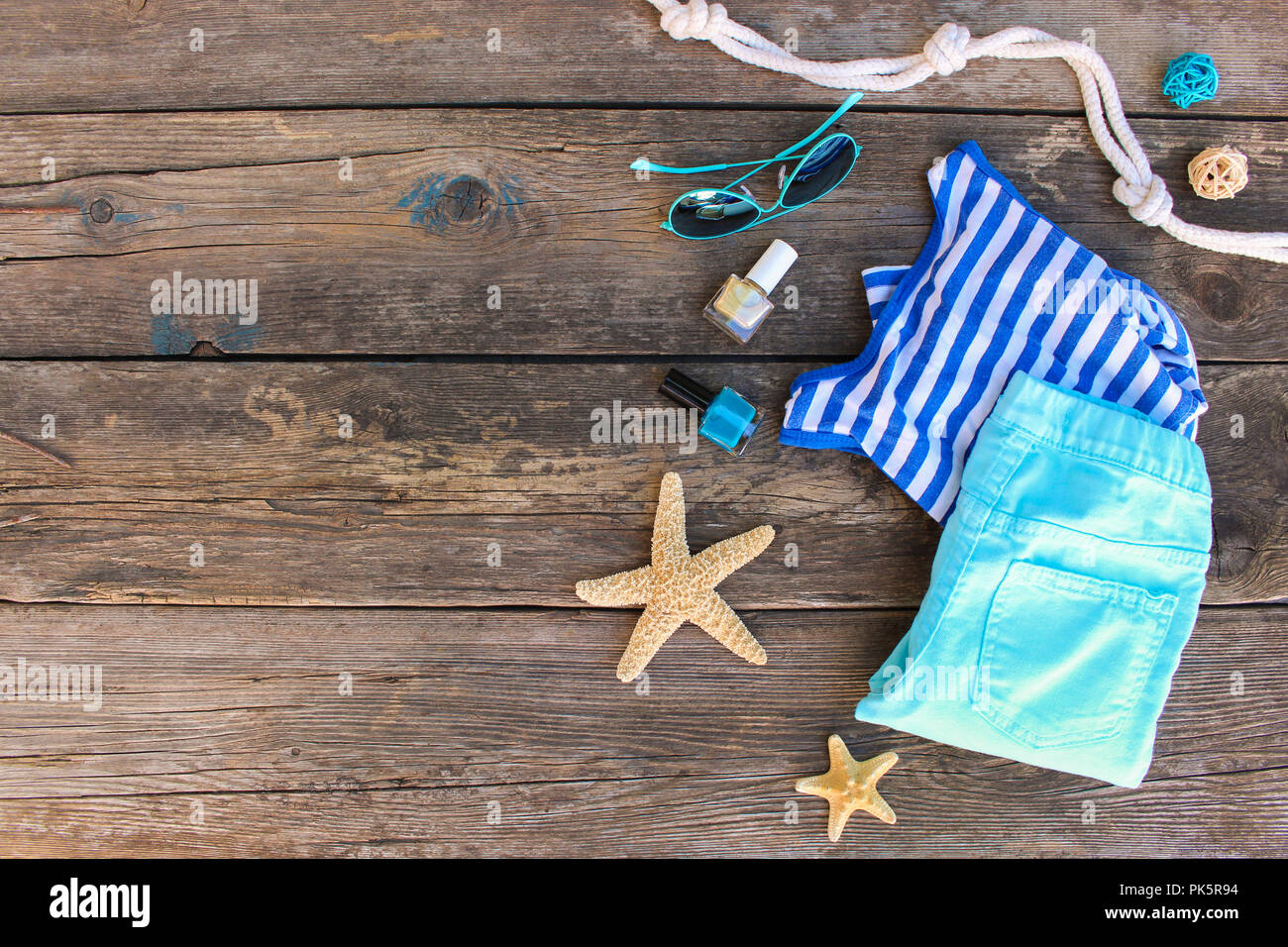 Women's summer clothes and accessories on old wooden background. Top view, flat lay. Stock Photo