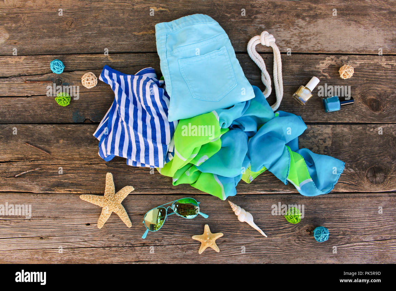 Summer clothes and accessories on old wooden background. Top view, flat lay. Stock Photo
