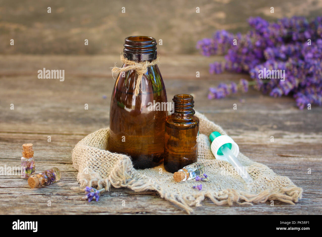 Lavender oil in different bottles on wooden background. Stock Photo